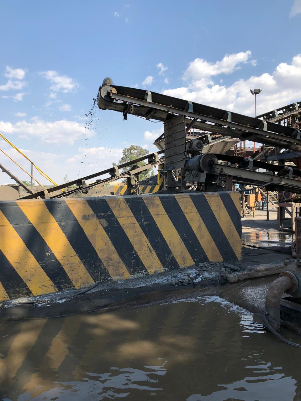 Conveyor system dropping material into wash pool